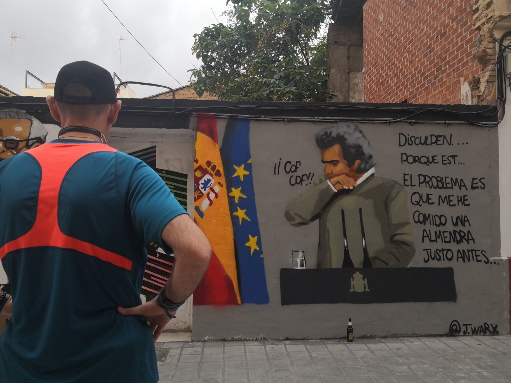 Un hombre mira un grafiti sobre Fernando Simón en Benimaclet, obra de J. Warx