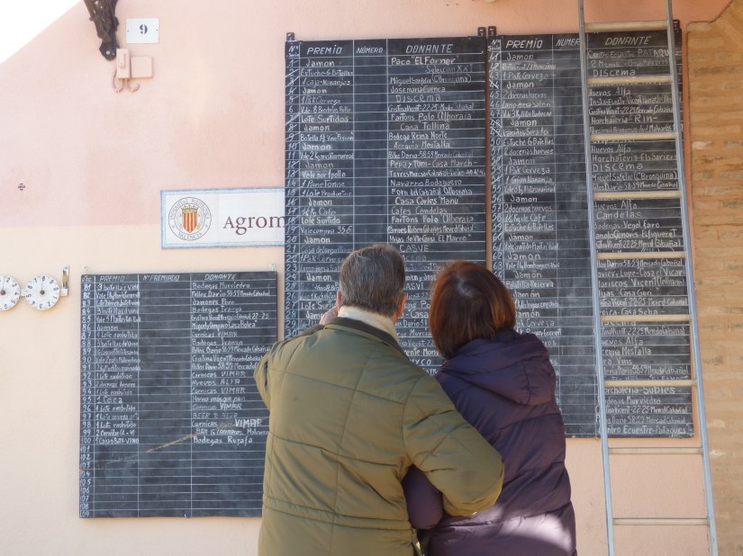 Dos personas contemplan el listado de premios de la rifa de la ermita de Vera