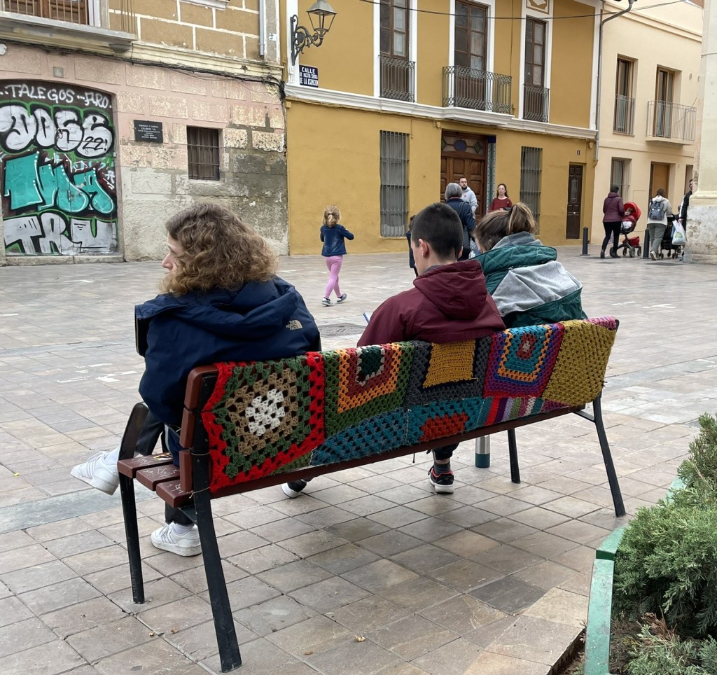 Tres personas descansan en un banco del centro histórico de Benimaclet